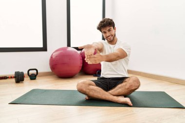 Genç İspanyol adam gülümsüyor spor merkezinde esniyor.