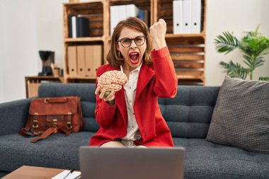 Muayenehanedeki genç esmer kadın elinde beyinle öfkeyle bağırıyor, öfkeyle bağırıyor ve el kaldırıyor. 