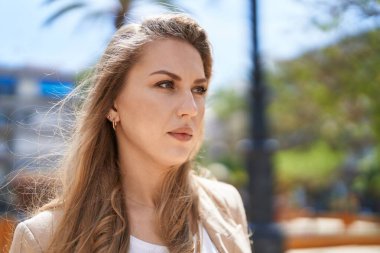 Parkta duran rahat yüzlü genç sarışın kadın.