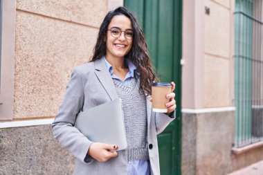 Sokakta dizüstü bilgisayar içen Latin kökenli genç bir yönetici.