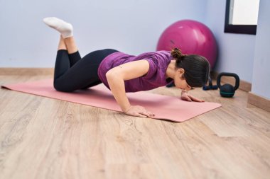 Genç kadın spor merkezinde şınav çekiyor.