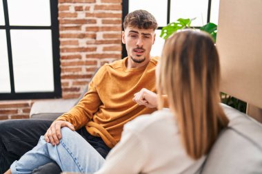 Genç adam ve kadın çift yeni evlerinde kanepede oturmuş sohbet ediyorlar.