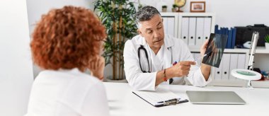 Doktor üniforması giyen orta yaşlı bir adam ve kadın klinikte tıbbi danışmanlık yapıyorlar.