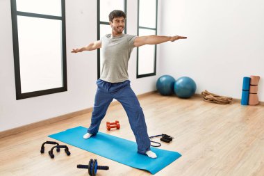 Genç İspanyol sporcu gülümsüyor. Spor merkezinde yoga eğitimi alırken mutlu..