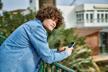 Genç İspanyol adam parkta akıllı telefon kullanıyor.