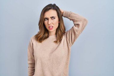 Young woman standing over isolated background confuse and wondering about question. uncertain with doubt, thinking with hand on head. pensive concept. 