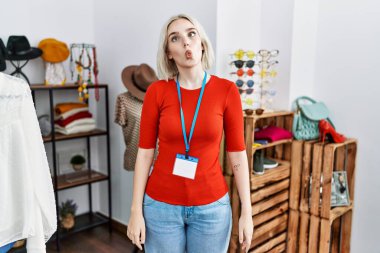 Young caucasian woman working as manager at retail boutique making fish face with lips, crazy and comical gesture. funny expression. 