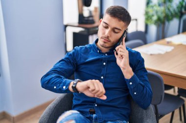 Genç İspanyol iş adamı. Akıllı telefondan konuşuyor. Ofise bakıyor.