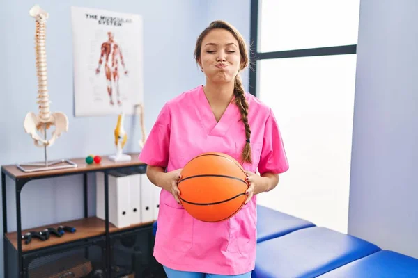 Young Hispanic Woman Working Physiotherapy Clinic Holding Basketball Ball Puffing — Stock Photo, Image