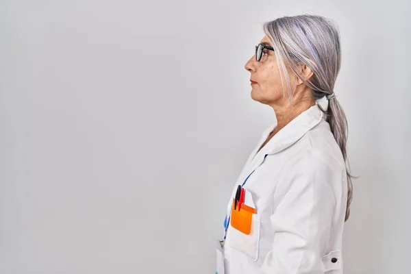 Middle age woman with grey hair wearing scientist robe looking to side, relax profile pose with natural face with confident smile.