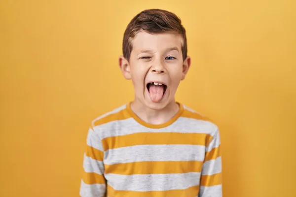 年轻的高加索小孩站在黄色的背景上 带着滑稽的表情伸出舌头 高兴极了 情感概念 — 图库照片