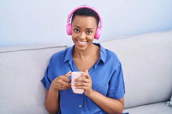 African american woman listening to music drinking coffee at home