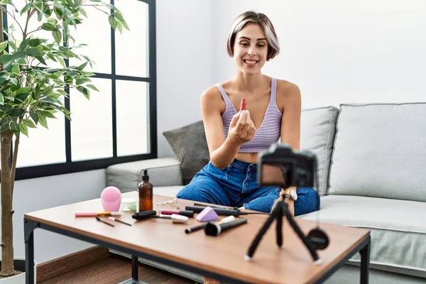 Makyaj hocası olan beyaz bir kız evdeki kanepede oturuyor..