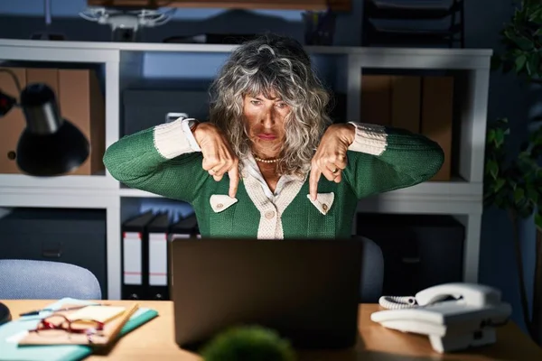 指で方向を示す 悲しいと動揺を指して コンピュータのラップトップを使用して夜に働く中世の女性は 不幸なと落ち込んで — ストック写真