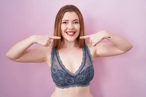 Roodharige Vrouw Draagt Lingerie Roze Achtergrond Glimlachend Vrolijk Tonen Wijzen — Stockfoto