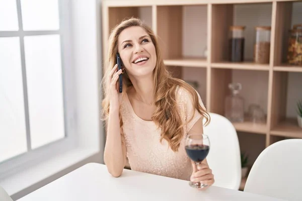 Mujer Rubia Joven Hablando Teléfono Inteligente Bebiendo Vino Casa —  Fotos de Stock