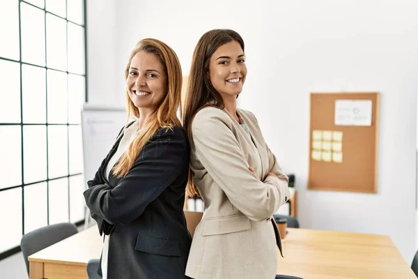 Mother and daughter business workers smiling confident standing with arms crossed gesture at office