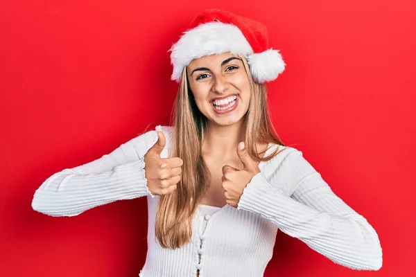 美丽的他的惊慌失措的女人戴着圣诞礼帽成功地做着积极的手势 竖起大拇指微笑着 快乐地 快乐的表达和胜利的姿态 — 图库照片