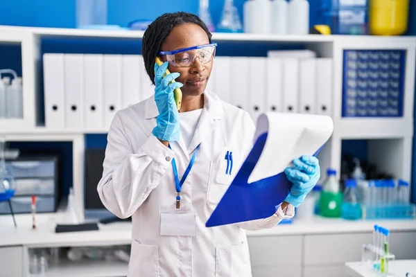 アフリカ系アメリカ人女性科学者の制服を着た女性がスマートフォンの研究室で — ストック写真