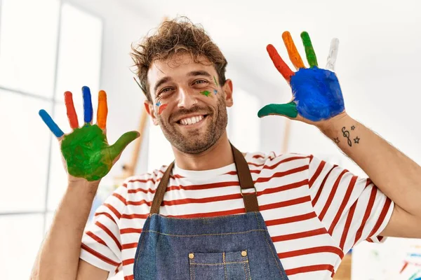 Młody Latynos Uśmiecha Się Pewnie Pokazując Kolorowe Dłonie Dłoni Studio — Zdjęcie stockowe