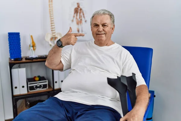 Hombre Caucásico Mayor Clínica Fisioterapia Sosteniendo Muletas Sonriendo Alegre Mostrando —  Fotos de Stock