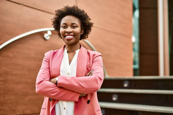 Beautiful business african american woman with afro hair smiling happy and confident outdoors at the city