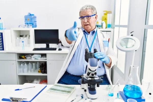 Starszy Biały Mężczyzna Pracujący Laboratorium Naukowym Wskazujący Palcem Kamerę Szczęśliwą — Zdjęcie stockowe