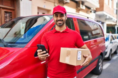 Genç İspanyol kurye sokakta akıllı telefon paketi kullanıyor.