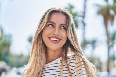Young blonde woman smiling confident looking to the side at street