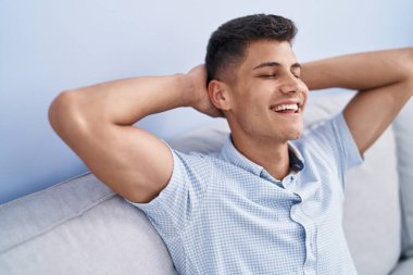 Genç İspanyol adam, ellerini başının üstüne koyup evinde kanepede oturarak rahatladı.