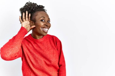 İzole edilmiş arka planda rahat kıyafetler giyen genç Afro-Amerikalı bir kadın. Dedikodulara ve dedikodulara kulak misafiri olarak gülümsüyor. Sağırlık kavramı. 