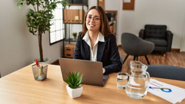 Ofiste çalışan genç İspanyol iş kadını laptopu kullanıyor.