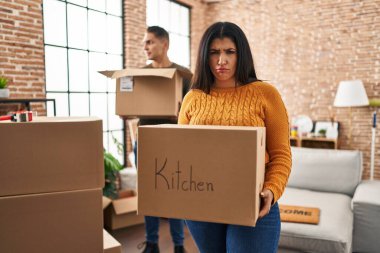 Karton kutularla dolu yeni bir eve taşınan genç çift şüpheci ve gergin, sorun yüzünden somurtuyorlar. negatif kişi. 