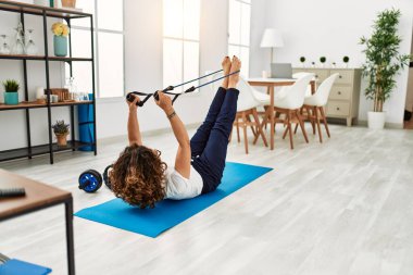 Olgun İspanyol kadın evdeki oturma odasında lastik bantlarla egzersiz yapıyor.