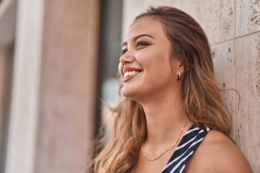 Young beautiful hispanic woman smiling confident looking to the side at street