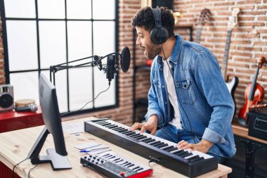Genç Arap müzisyen müzik stüdyosunda piyano klavyesi çalıyor.