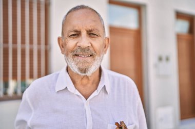 Kıdemli adam sokakta kendinden emin gülümsüyor.