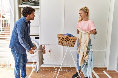 Gülümseyen genç çift evde çamaşır ipinde mutlu mesut giyiniyor..