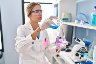 Laboratuvarda test tüpüne sıvı döken genç İspanyol bilim kadını.