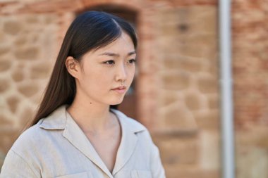 Çinli kadın sokakta rahat bir ifadeyle yan tarafa bakıyor.