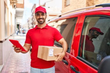 Genç İspanyol kurye sokakta dokunmatik ped paketi kullanıyor.