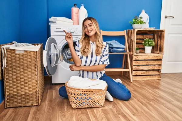 Ung Blond Kvinna Gör Tvätt Hemma Ler Glad Pekar Med — Stockfoto