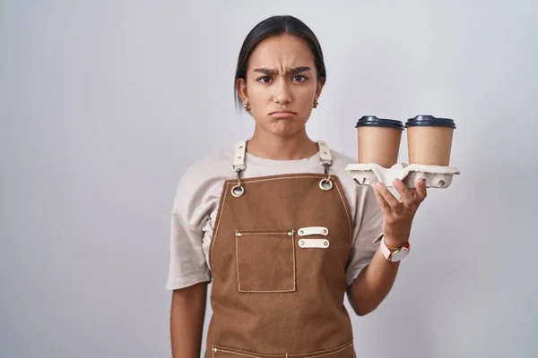 Mujer Hispana Joven Con Delantal Camarera Profesional Sosteniendo Café Escéptico —  Fotos de Stock
