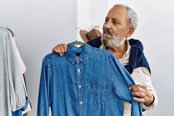Älterer Grauhaariger Mann Lächelt Selbstbewusst Und Hält Hemd Vor Bekleidungsgeschäft — Stockfoto