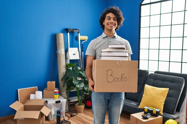 Jovem Hispânico Sorrindo Confiante Segurando Livros Pacote Nova Casa — Fotografia de Stock