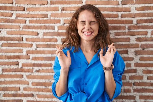 Beautiful Brunette Woman Standing Bricks Wall Gesturing Finger Crossed Smiling — Stock Photo, Image