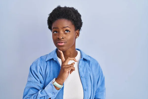 Африканская Американка Стоящая Синем Фоне Думающая Сомнении Пальцем Подбородке Глядя — стоковое фото