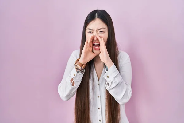 中国的年轻女子站在粉色的背景上 用双手捂着嘴大喊大叫 — 图库照片