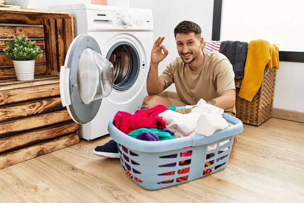 Kirli Çamaşırları Çamaşır Makinesine Koyan Yakışıklı Genç Adam Gülümsüyor Parmaklarıyla — Stok fotoğraf
