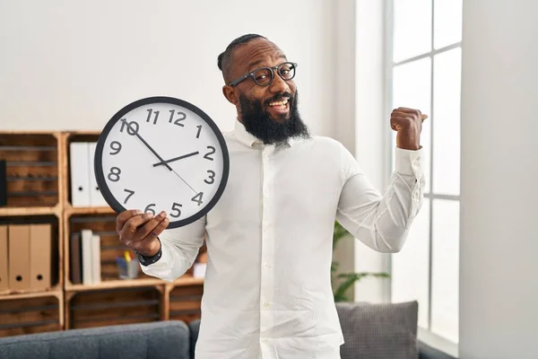 Африканский Американец Держит Большие Часы Офисе Указывая Пальцем Вверх Сторону — стоковое фото